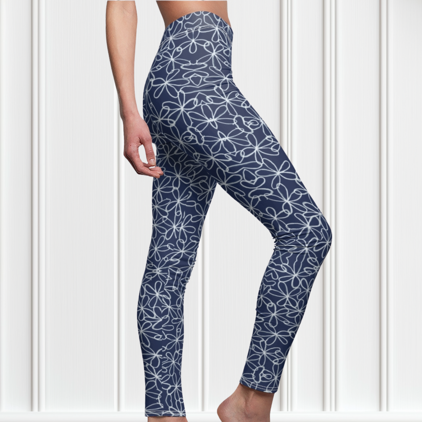 A pair of navy blue women's high waisted leggings with a white floral pattern all over the handmade pants.