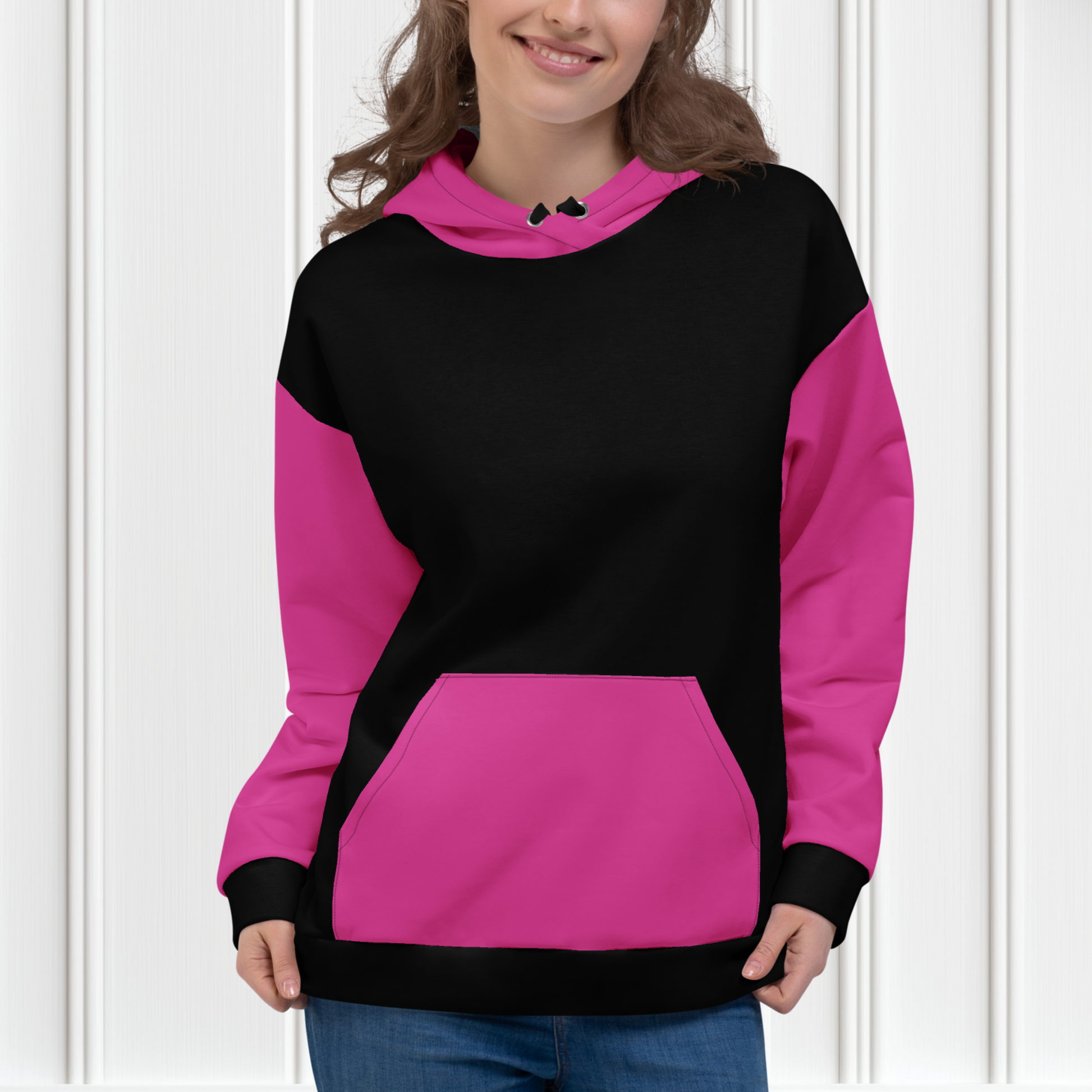 A women's custom oversized handmade hoodie, on the front and the back of the hoodie is the color black, the sleeves, front kangaroo pocket and hood are all a bright pink color, the strings of the sweater are black.