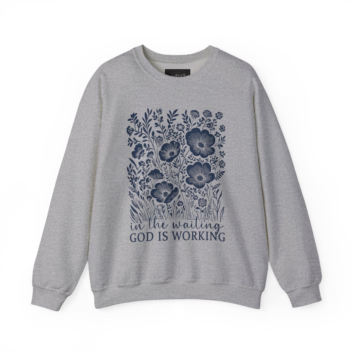 On the front of this custom women's Christian pullover sweatshirt are a bunch of wildflowers with the words in the waiting God is working underneath the flowers.