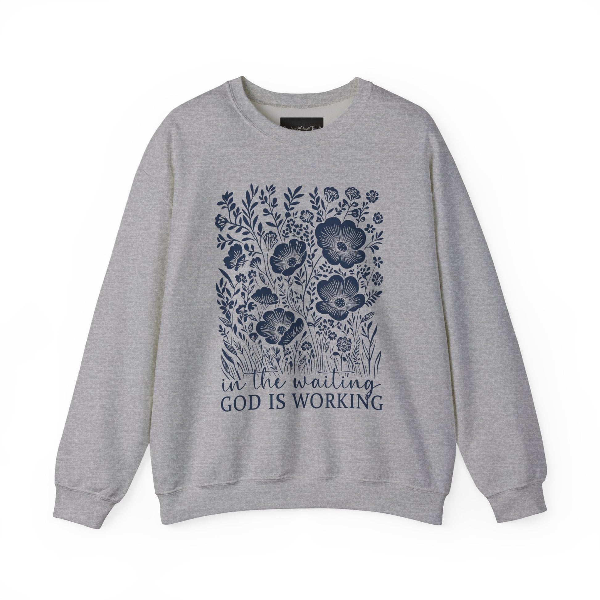 On the front of this custom women's Christian pullover sweatshirt are a bunch of wildflowers with the words in the waiting God is working underneath the flowers.
