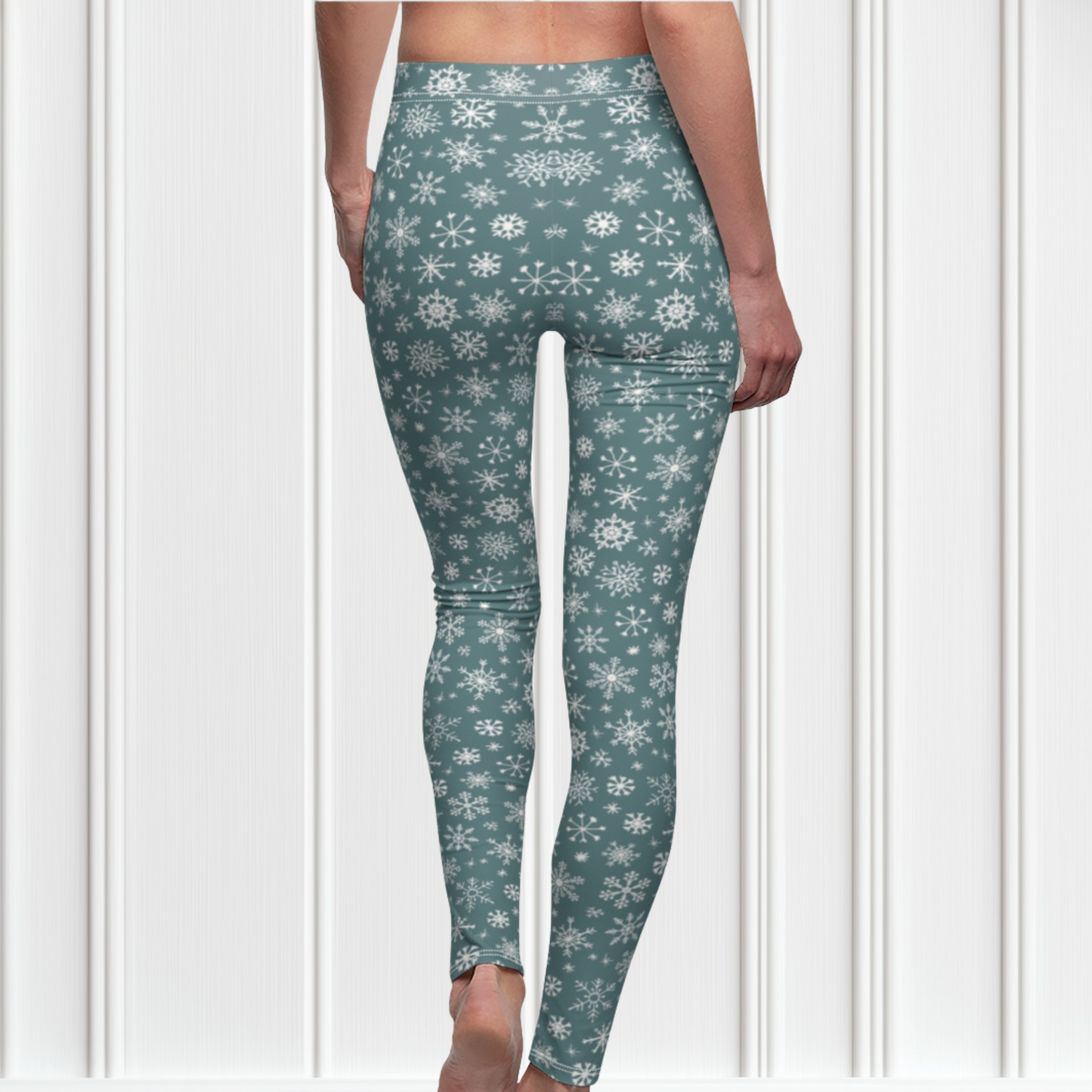 A pair of high waisted custom women's leggings that are a light blue in color and have white snowflakes all over the pants, perfect for Christmas.
