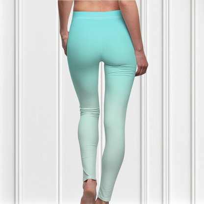 A pair of women's high waisted ankle length leggings that have a ombre pattern that starts as a medium ocean blue at the waistline then fades to a very light sky blue at the ankles of the pant.