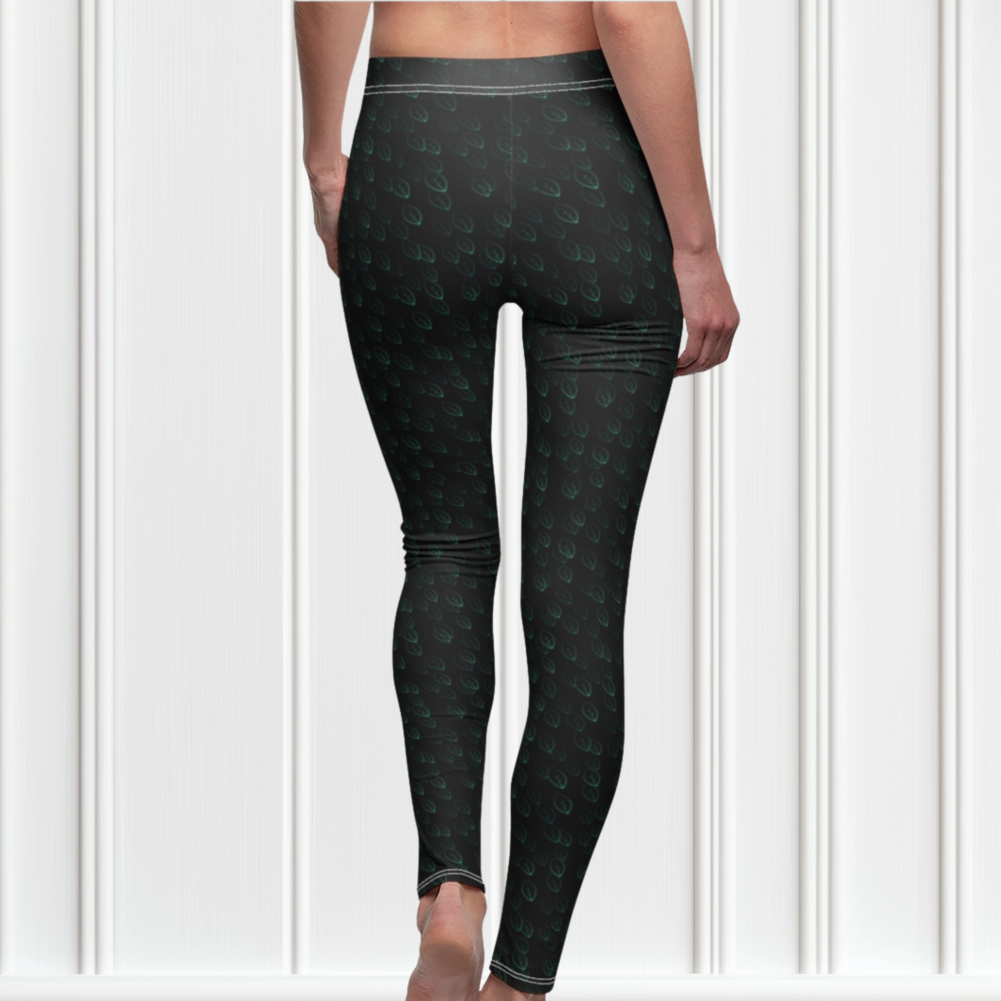 Custom high waisted women's leggings that are all black in color with a pattern of light green leaves all over the pants.
