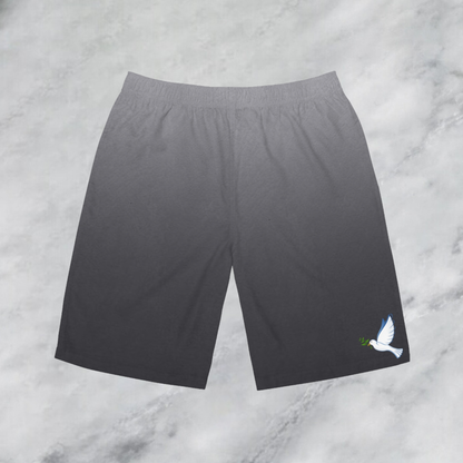 These custom men's board shorts feature a unique design with a ombre pattern starting with a light grey at the top then fading to a dark grey at the bottom, there is a symbol of a dove carrying a fig leaf on the front left side of the shorts just at the knee.