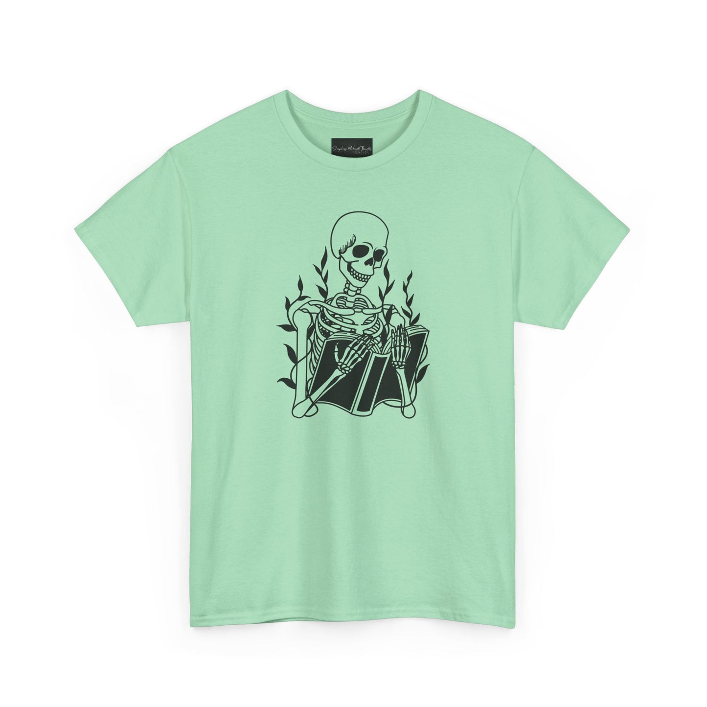 On the front of this custom unisex short sleeve shirt is a large image of a skeleton reading a book, there are vines with leaves on them behind the skeleton.