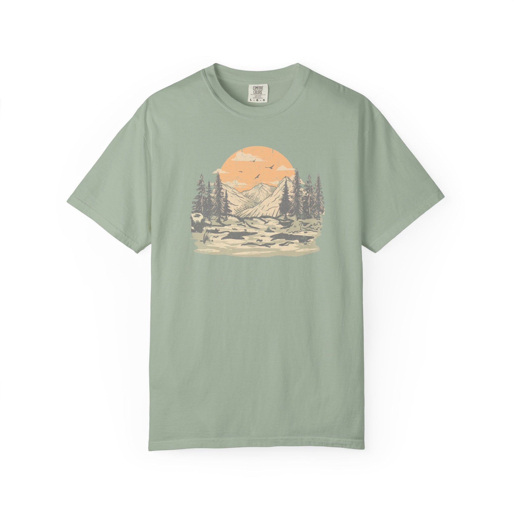 On the front of this custom comfort colors short sleeve t-shirt is a large vintage image of a large valley that opens up to a mountain range with pine trees , there is a large sun in the background with birds flying all around, this t-shirt is completely vintage.