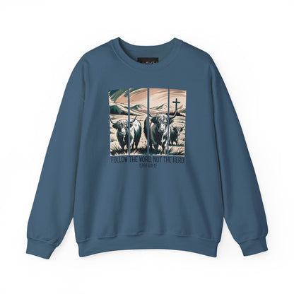 On the front of this Christian pullover sweatshirt is the image of cows standing in a pasture that is in a valley surrounded by mountains, there is a Jesus cross behind the cows, underneath the image is the scripture Follow the word, not the herd Isiah 8:11-13
