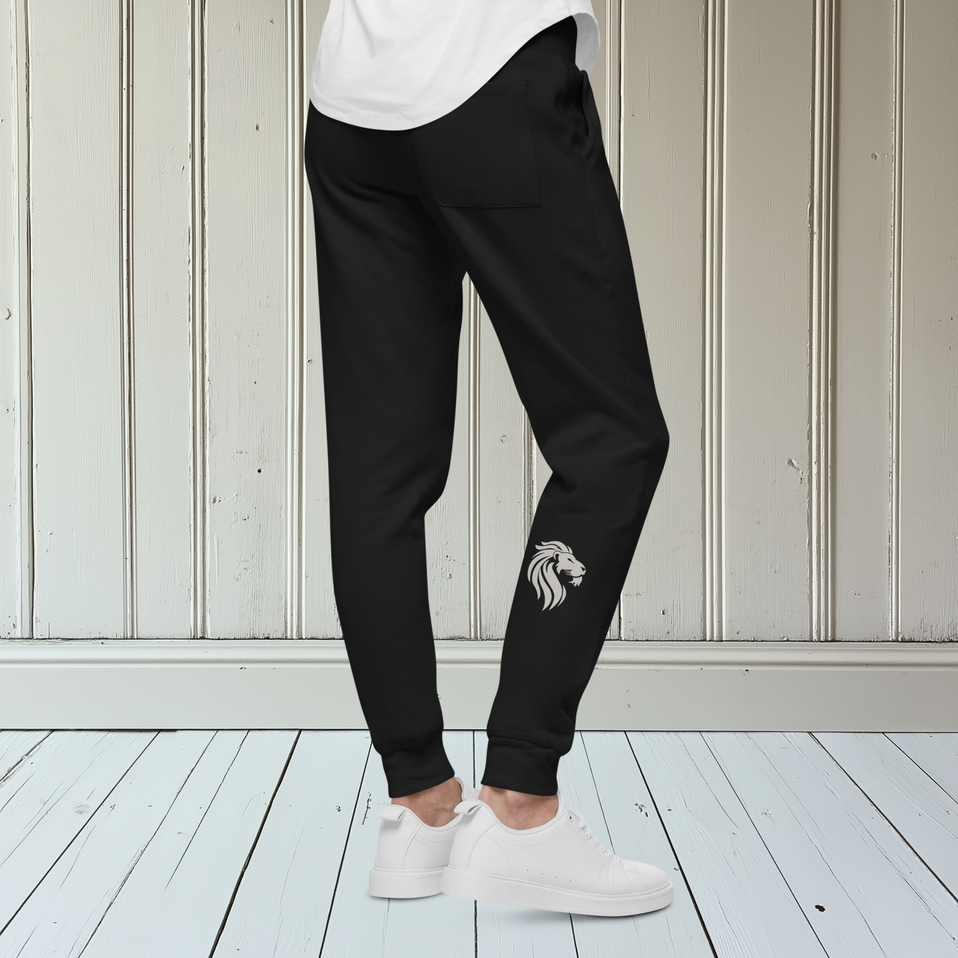 A pair of super soft custom unisex fleece sweatpants with a male lion head on the back calf of the right leg embroidered in silver.