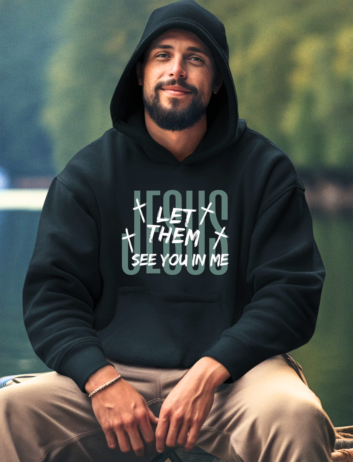 On the front of this custom Christian hoodie it says Jesus in large letters with the words Let them see you in me overlayed overtop of Jesus, there are crosses around the wording.