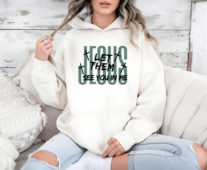 On the front of this custom Christian hoodie it says Jesus in large letters with the words Let them see you in me overlayed overtop of Jesus, there are crosses around the wording.