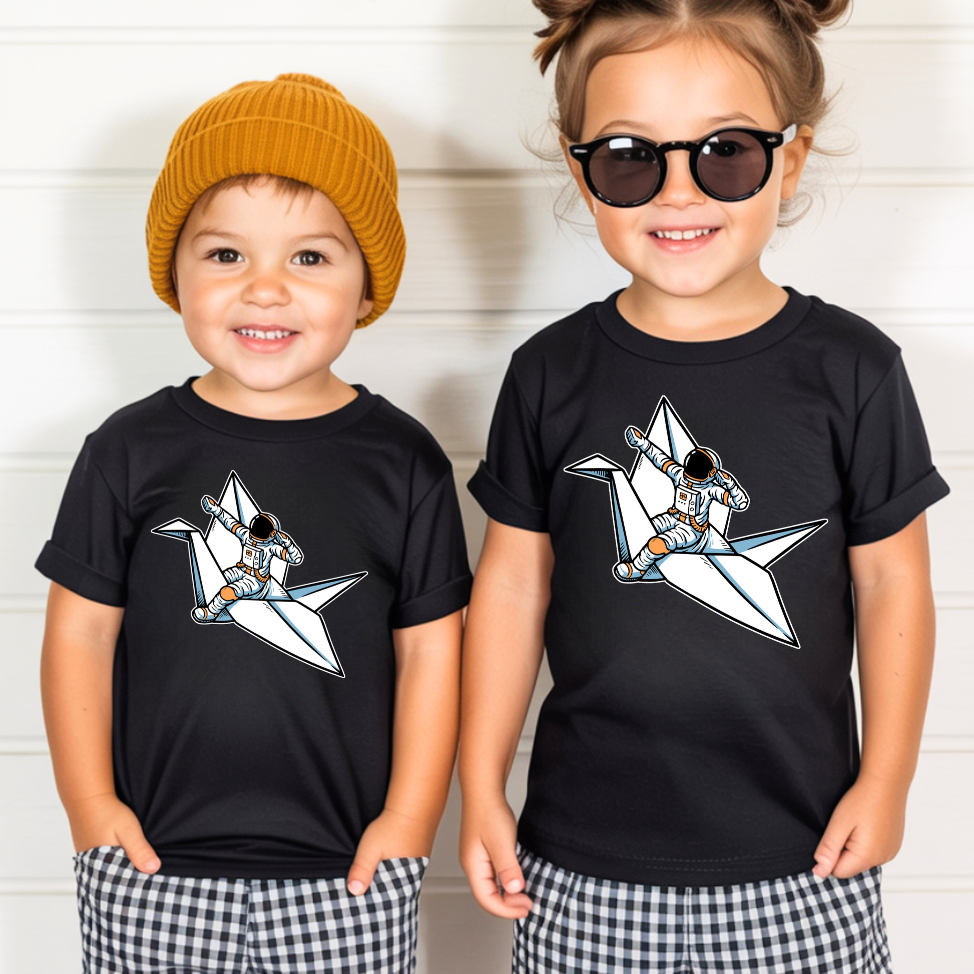 On the front of this custom kids t-shirt is an image of a astronaut flying on a paper plane.