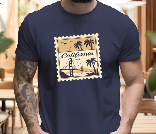 On the front of this custom vintage short sleeve shirt is a California postage stamp with images of the golden gate bridge, palm trees and the ocean on it, the entire stamp is different shades of beige.