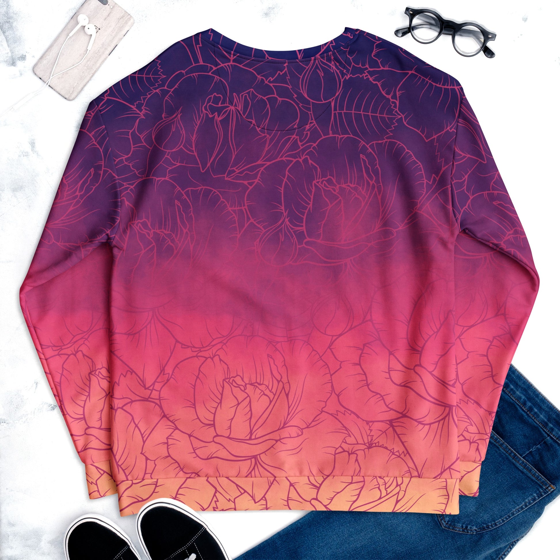 The sweater has a washed ombre pattern starting as a dark purple at the top of the neckline then fading to a light purple then to a bright pink then to a blush pink at the bottom, there is a purple floral pattern imposed on the top of the sweater.