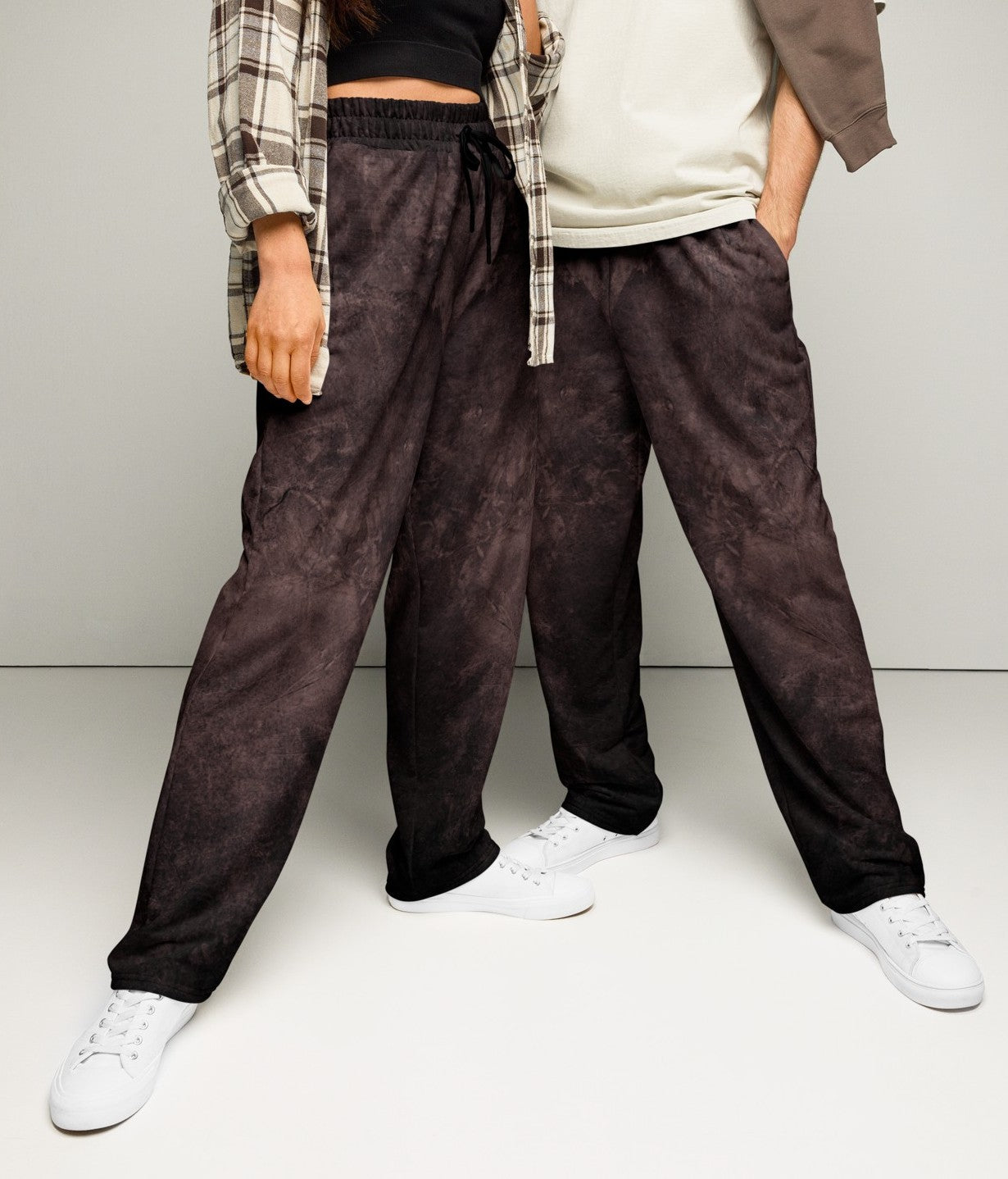 A pair of custom wide leg joggers that have a dark washed brown pattern all over the pants and come with a black string around the waistband.