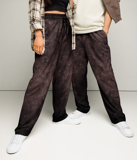 A pair of custom wide leg joggers that have a dark washed brown pattern all over the pants and come with a black string around the waistband.