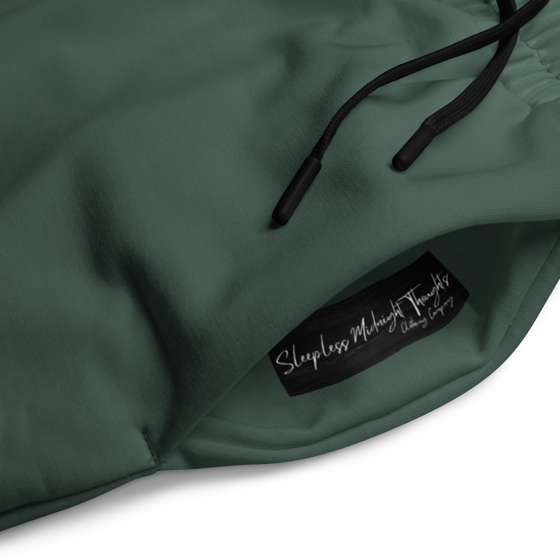 A custom pair of handmade unisex joggers that have an ombre pattern, the top of the pants have a teal green color that shifts to black at the bottom of the sweatpants, there is a black tie around the waist.