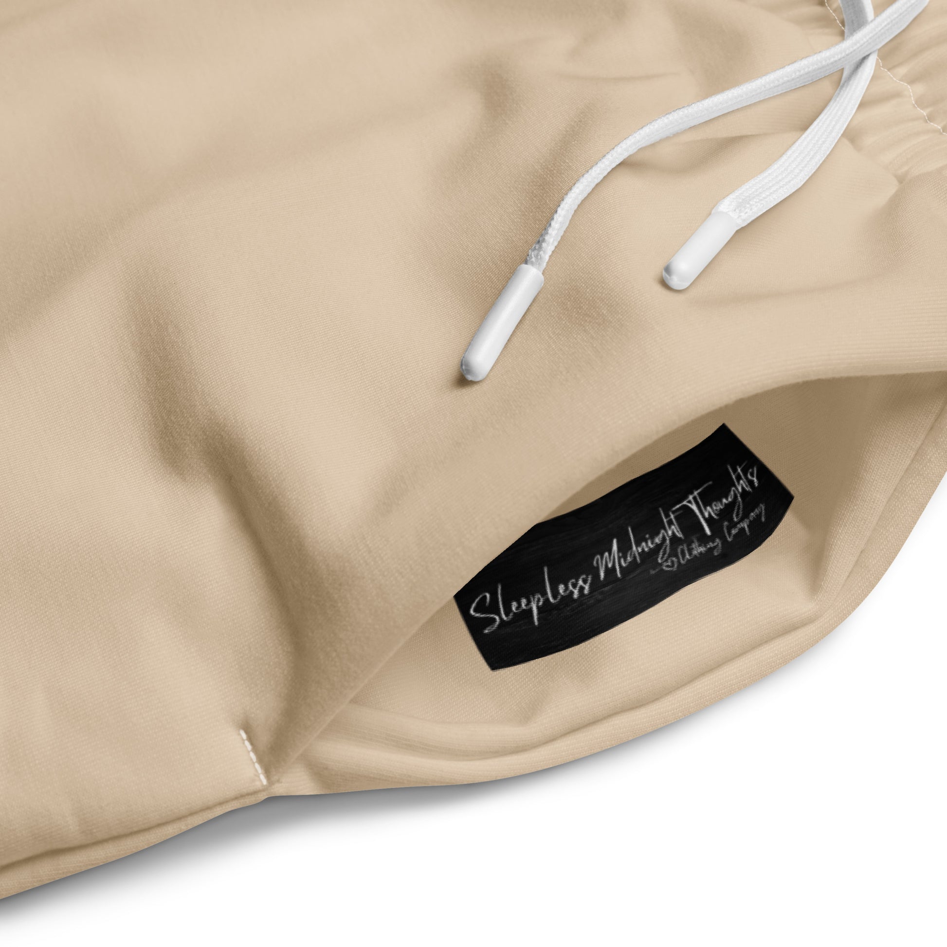 A pair of wide legged custom joggers that are light beige in color with white strings around the waistband.