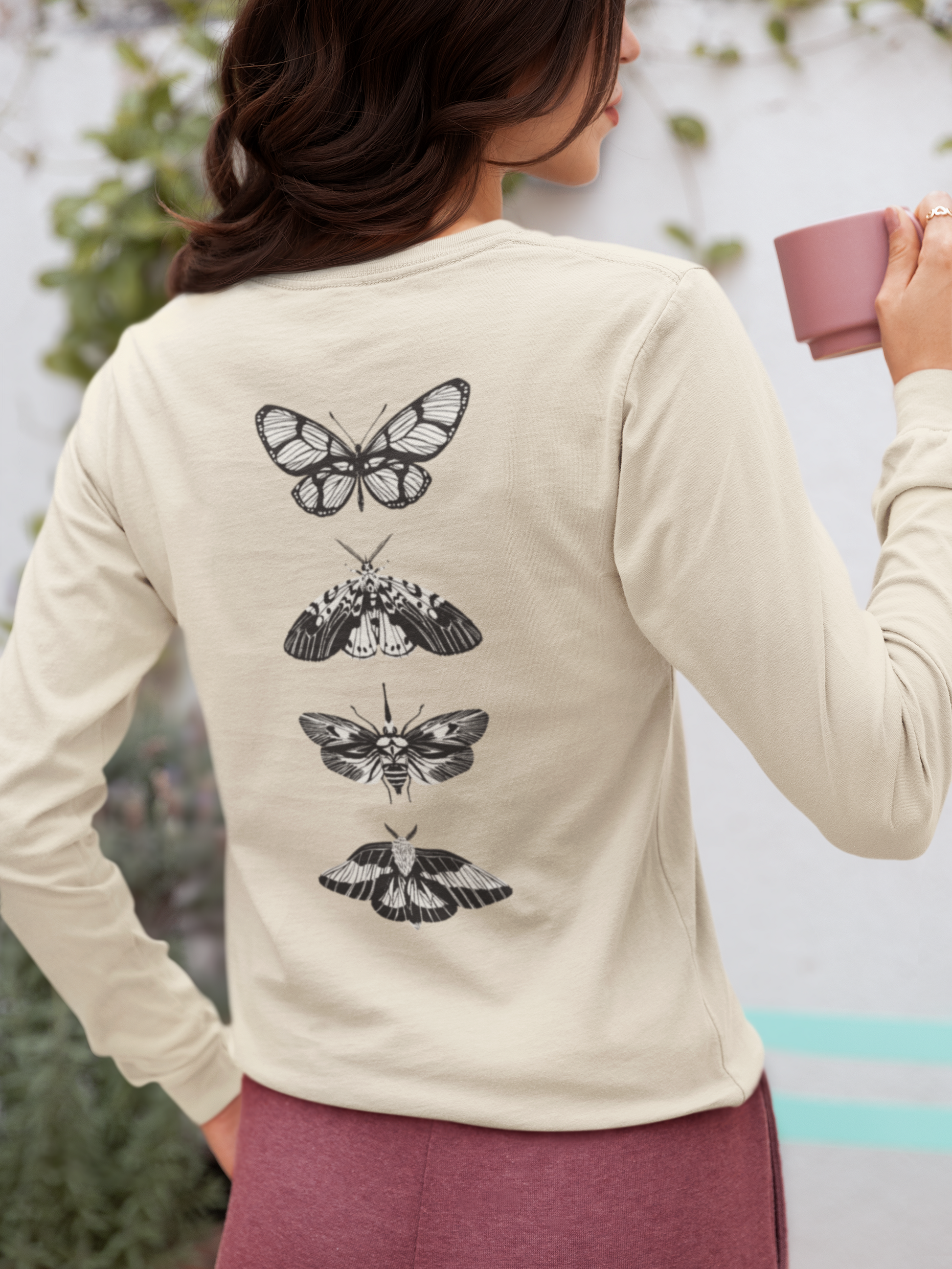 On the back of this long sleeve women's shirt right in between the shoulder blades is a row of black and white butterflies, starting at the top of the back and headed to the bottom of the shirt.