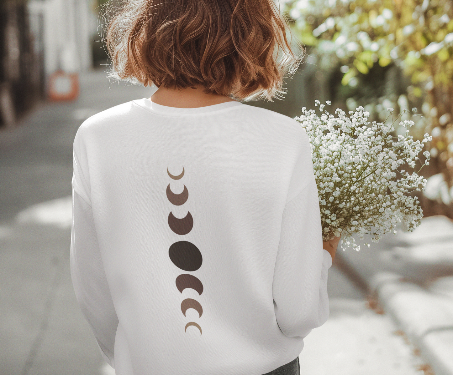 On the back of this custom unisex long sleeve t-shirt from the top of the shirt to the bottom are 7 images of the moon showing the moons cycle, every moon is a different shade of brown.