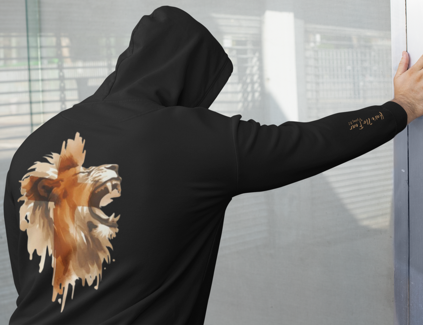 This custom Christian unisex hoodie features a image of a majestic male lion roaring with a Jesus cross overlayed overtop of the lion on the back of the hoodie, the bible verse Have No Fear Psalms 27:1 is on the right sleeve in gold cursive font.
