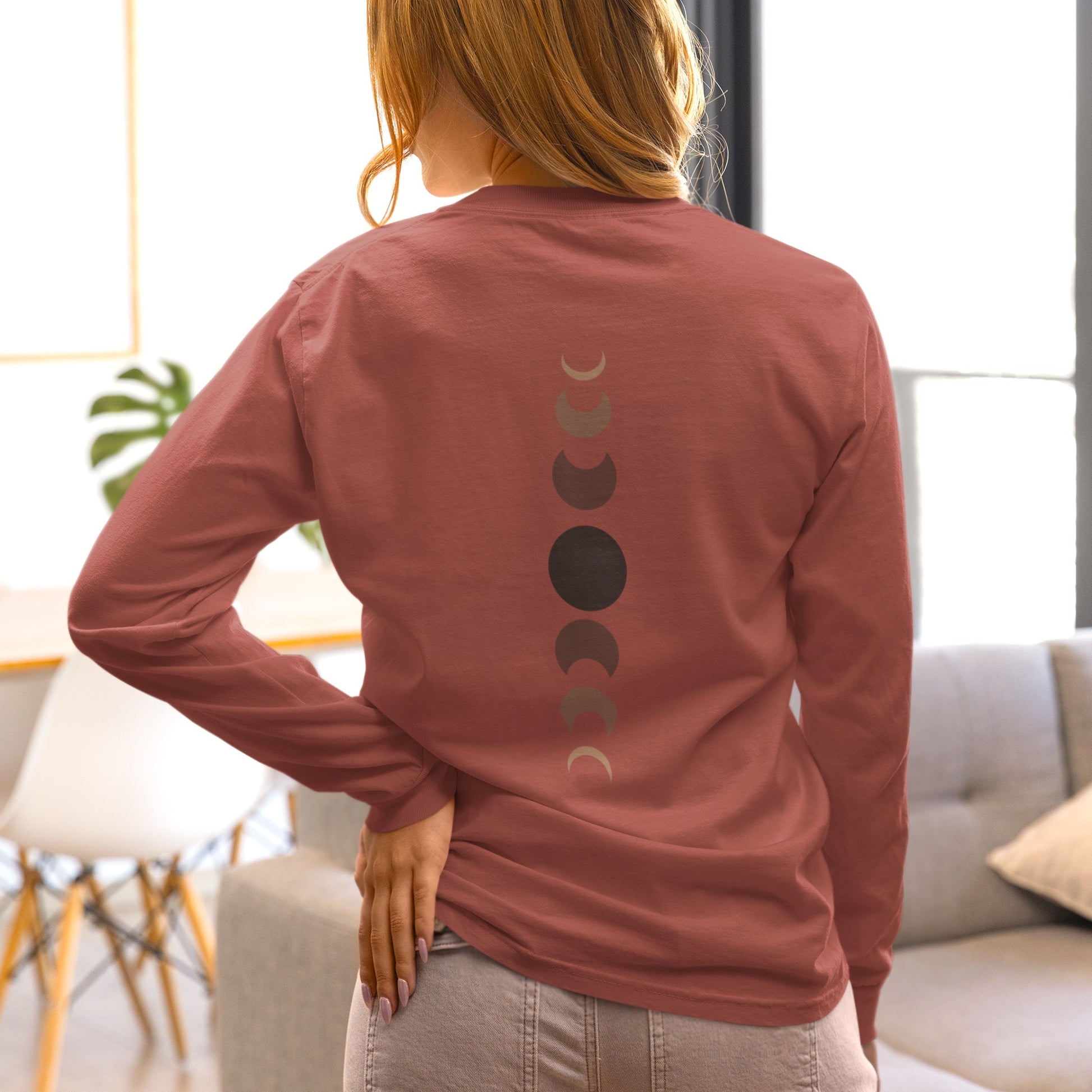 On the back of this custom unisex long sleeve t-shirt from the top of the shirt to the bottom are 7 images of the moon showing the moons cycle, every moon is a different shade of brown.