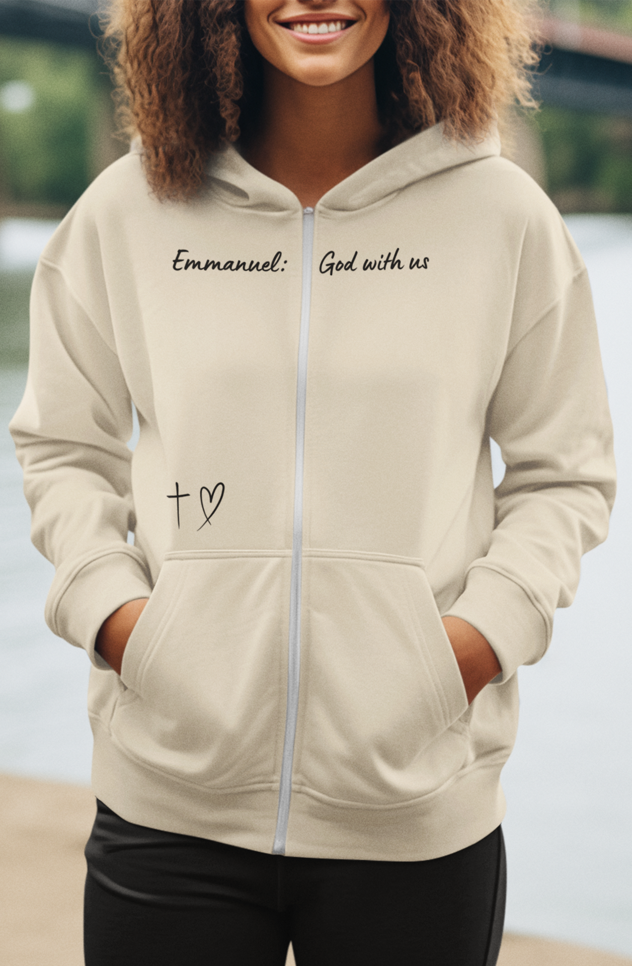 This Unisex Heavy Blend™ Full Zip Hooded Sweatshirt features the words Emmanuel God With Us on the upper chest and an image of a cross with a heart above the pocket.