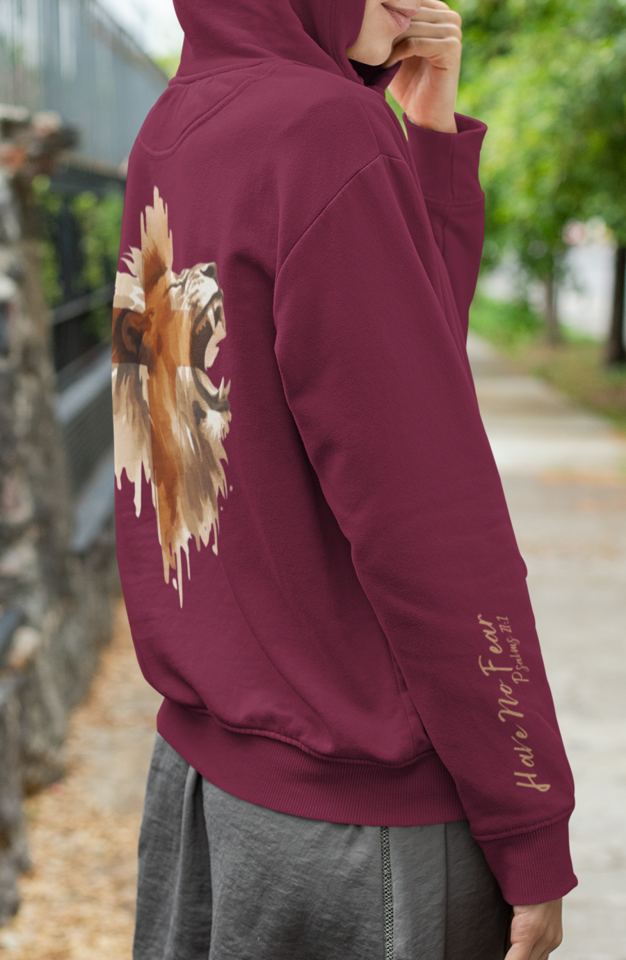This custom Christian unisex hoodie features a image of a majestic male lion roaring with a Jesus cross overlayed overtop of the lion on the back of the hoodie, the bible verse Have No Fear Psalms 27:1 is on the right sleeve in gold cursive font.