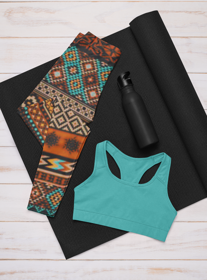 A pair of super soft handmade women's ankle length high waisted leggings. The pattern throughout the entire pair of pants is a orange, brown and blue Aztec pattern from the top of the pants to the bottom of the leggings.