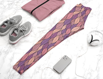 These custom colorful handmade women's leggings have a pattern of multicolored leaves from top to bottom, the leaves are light pink, purple, mauve and beige giving the leggings a vibrant look.