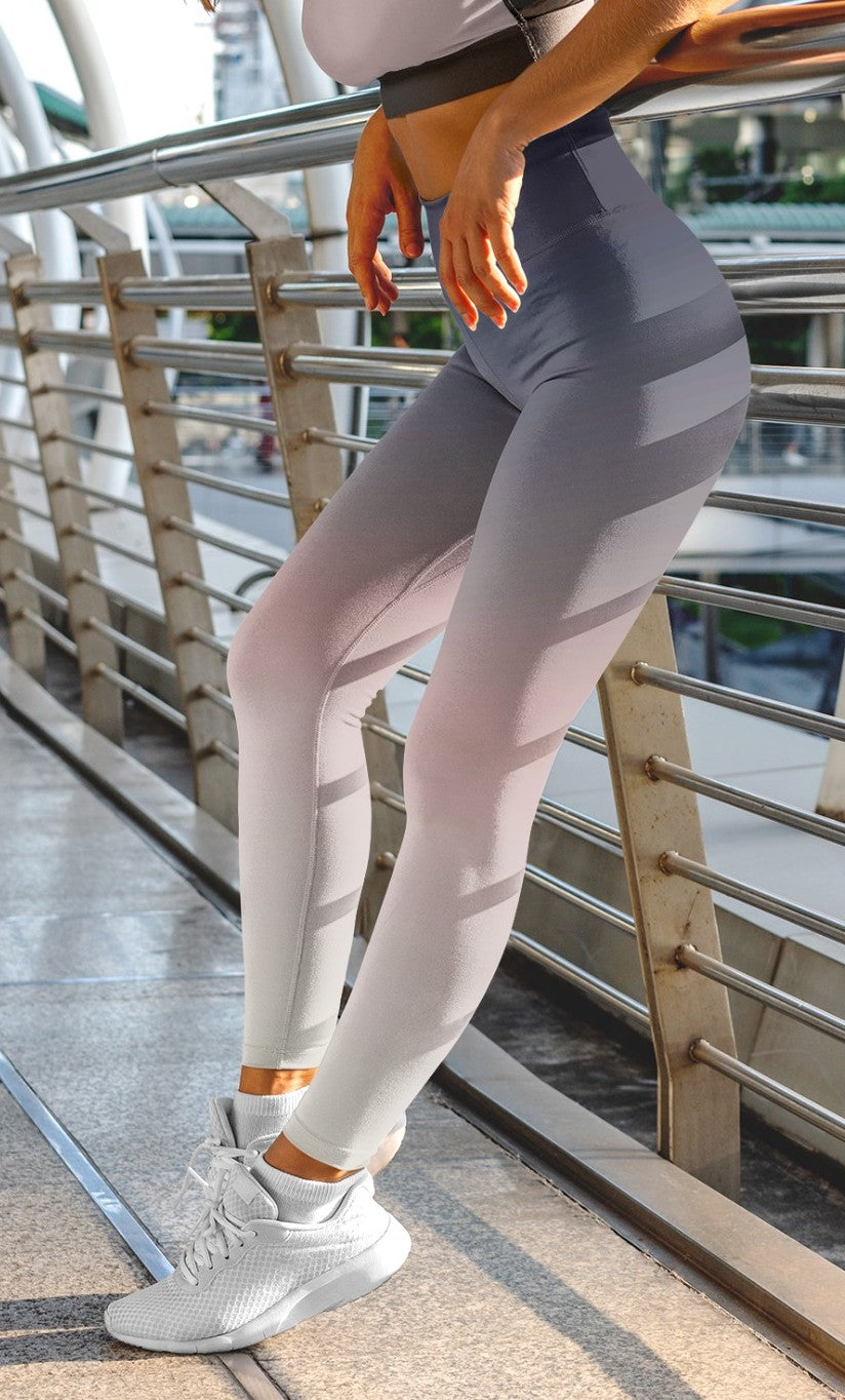 A pair of women's custom high waisted leggings that have an ombre pattern that starts as black at the top of the leggings then fades to a light pink in the middle then to a beige at the bottom of the pants.