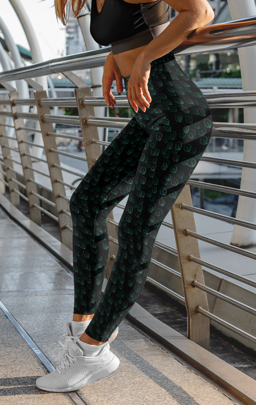 Custom high waisted women's leggings that are all black in color with a pattern of light green leaves all over the pants.