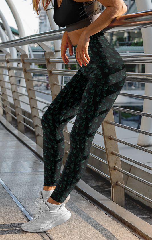 Custom high waisted women's leggings that are all black in color with a pattern of light green leaves all over the pants.