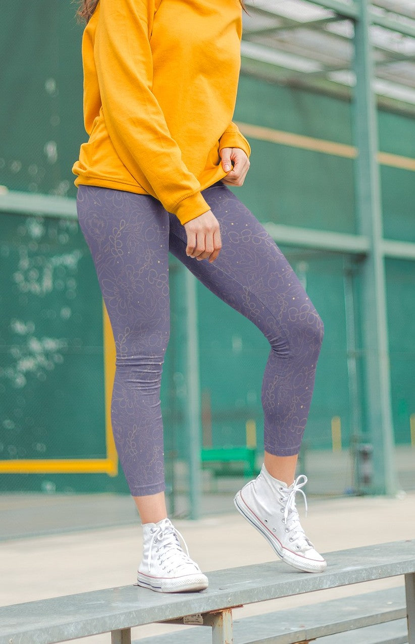 These custom handmade women's leggings are a dark purple with a beautiful gold floral pattern overlayed on the top.
