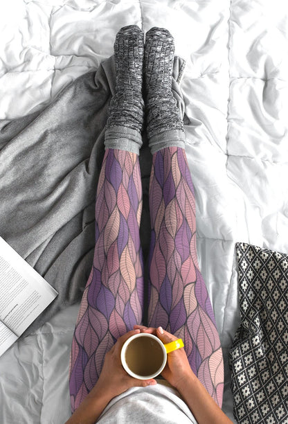 These custom colorful handmade women's leggings have a pattern of multicolored leaves from top to bottom, the leaves are light pink, purple, mauve and beige giving the leggings a vibrant look.