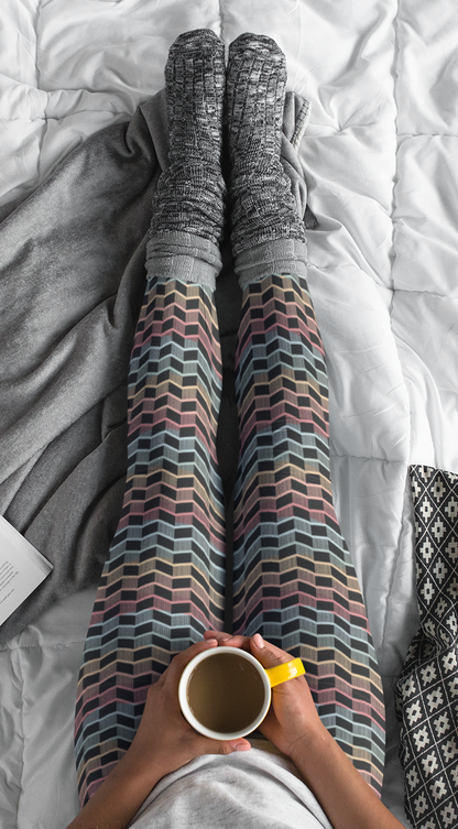 Custom women's leggings with rows of pastel red, yellow and blue from the top to the bottom of the leggings, there is a black abstract pattern overtop of the colors giving the leggings a 3D look.