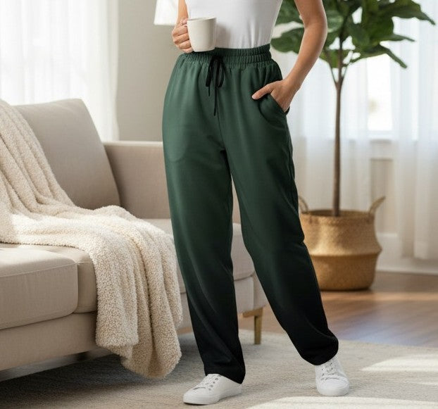 A custom pair of handmade unisex joggers that have an ombre pattern, the top of the pants have a teal green color that shifts to black at the bottom of the sweatpants, there is a black tie around the waist.