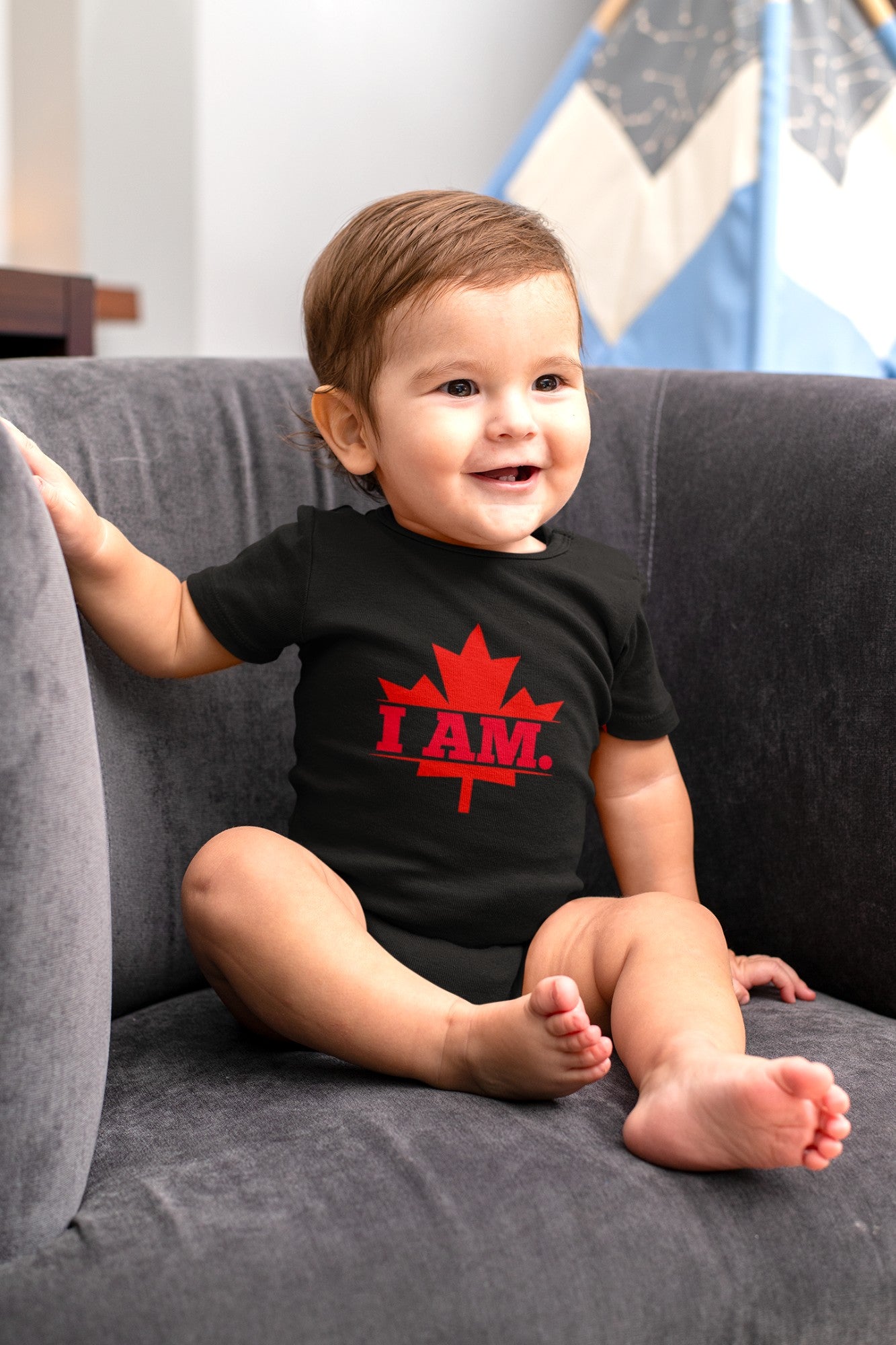 On the front of this custom infant short sleeve onesie is a image of a Canadian Maple leaf with the words I AM in the center of it in large block letters.