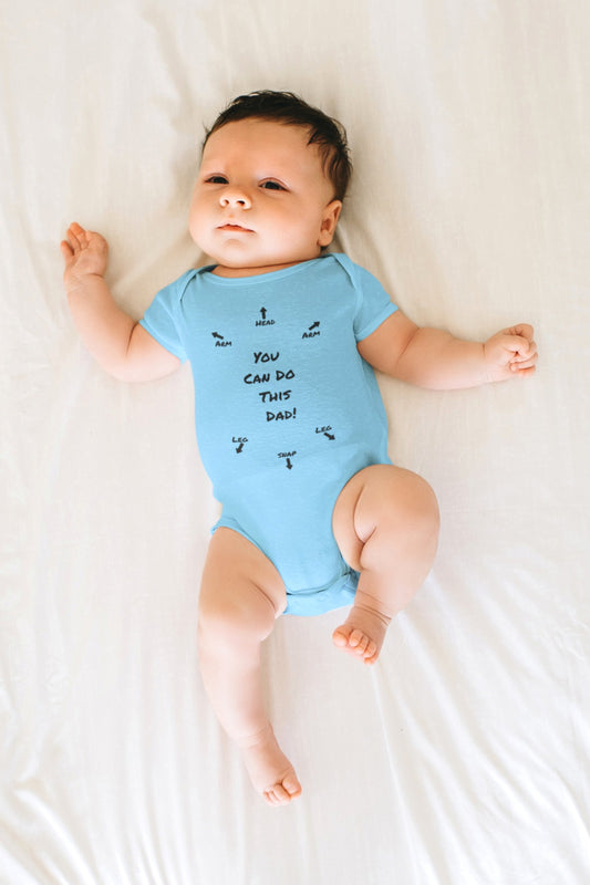 on the front of this custom infant onesie specifically meant for dads, are the words You can do this dad with arrows pointing where each leg and each arm goes along with were the babies head goes and where to close the snaps, a perfect diagram for a new father on how to put a onesie on a baby.