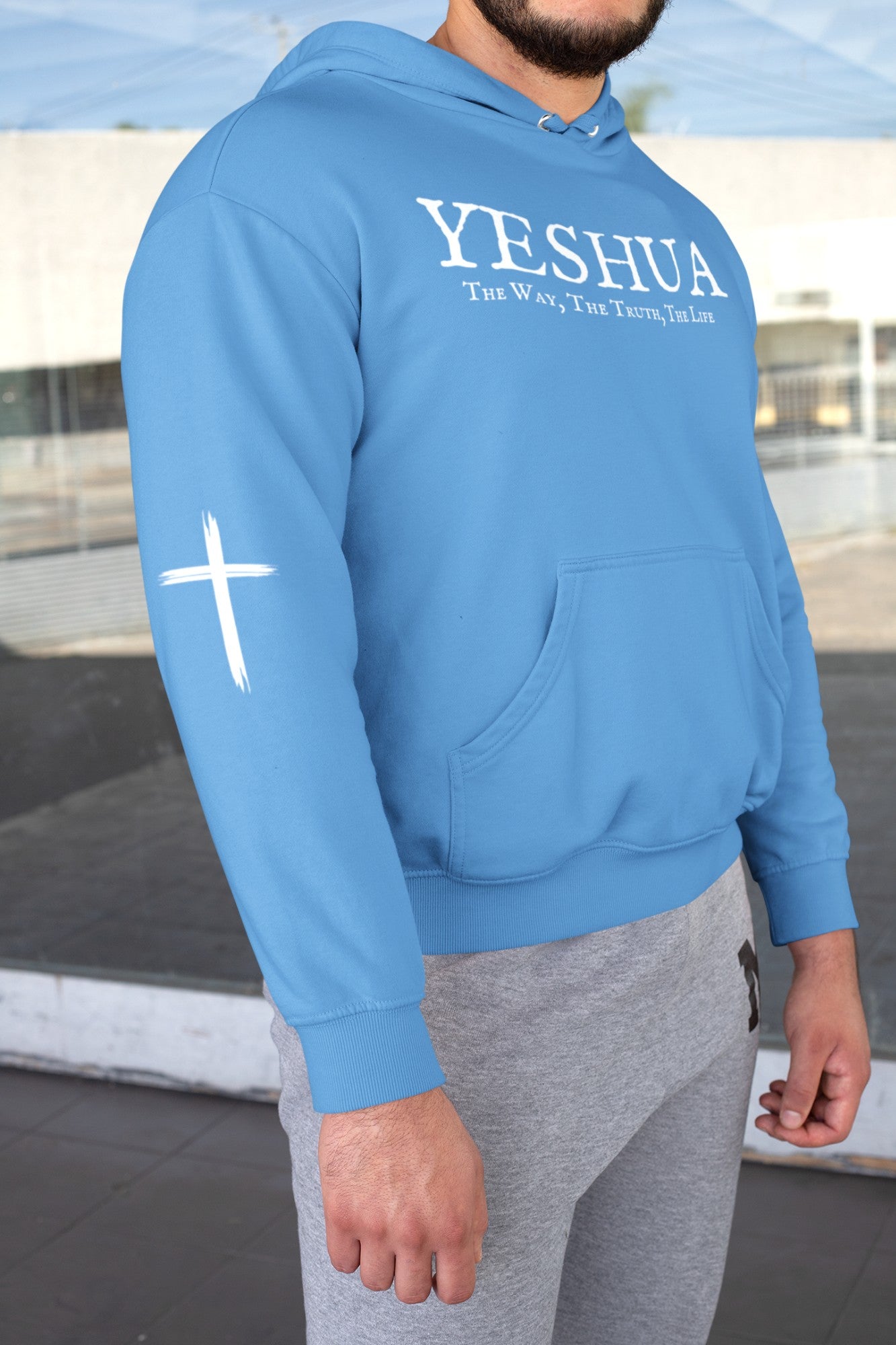 A custom handmade unisex Christian hooded sweater, on the front of the hoodie in white are the words Yeshua the same today, tomorrow and forever in an old style font, there is also a white Jesus cross on both sleeves of the hooded sweater right at the elbows.