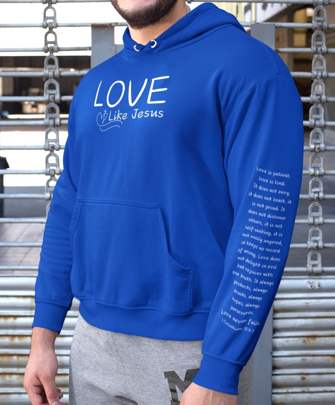 A cozy and warm custom Christian hoodie featuring a powerful message of love and faith. The front displays the word LOVE Like Jesus, accompanied by a cross with a heart. Each sleeve showcases the scripture 1 Corinthians 13:4-7