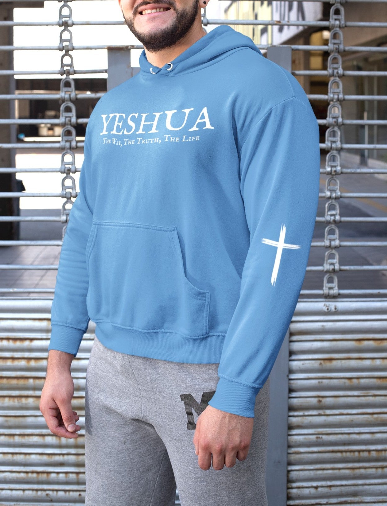 A oversized hoodie, on the front of the hoodie in white are the words Yeshua the same today tomorrow and forever in a old style font, there is also a white Jesus cross on both sleeves of the hooded sweater