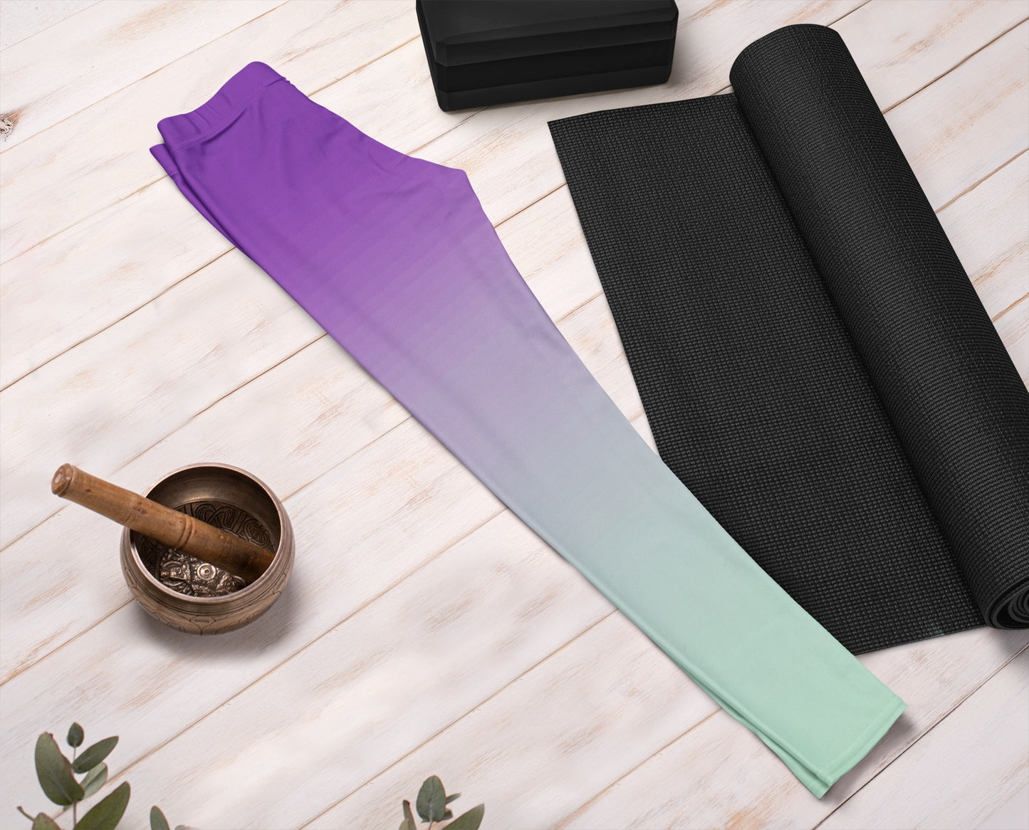 These high waisted handmade women's leggings have a ombre pattern with the top of the leggings being a deep purple and then it fading to a light turquoise blue at the bottom of the pants.