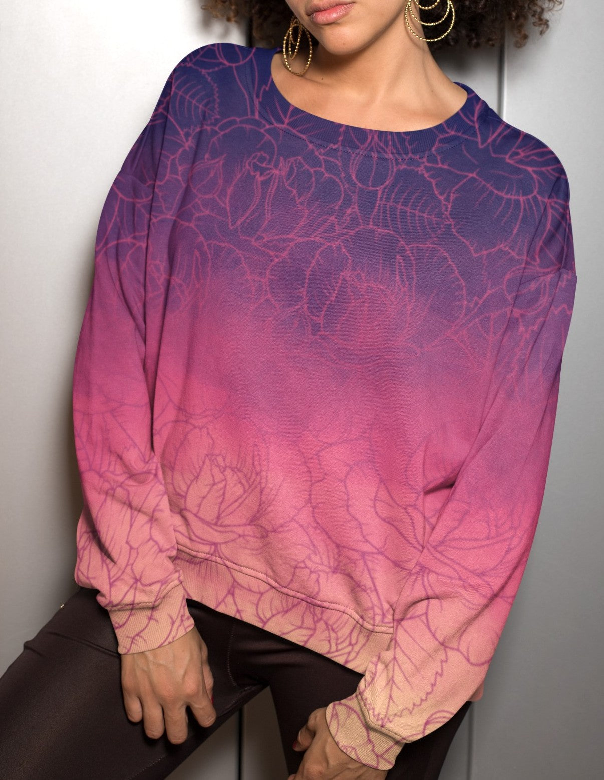 The sweater has a washed ombre pattern starting as a dark purple at the top of the neckline then fading to a light purple then to a bright pink then to a blush pink at the bottom, there is a purple floral pattern imposed on the top of the sweater.
