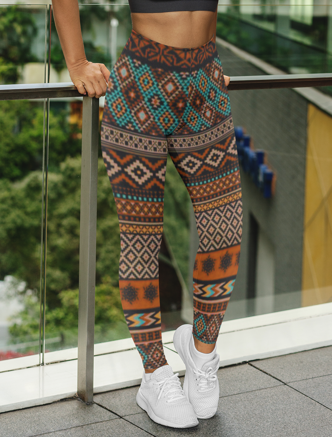 A pair of super soft handmade women's ankle length high waisted leggings. The pattern throughout the entire pair of pants is a orange, brown and blue Aztec pattern from the top of the pants to the bottom of the leggings.