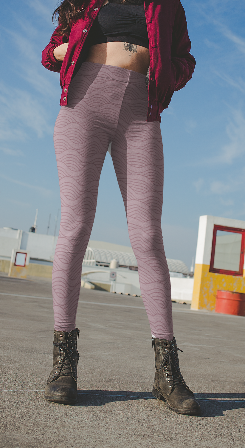 A pair of women's high waisted custom handmade leggings that are a light mauve in color, there are wavy lines throughout the pants that is a deep rose color.