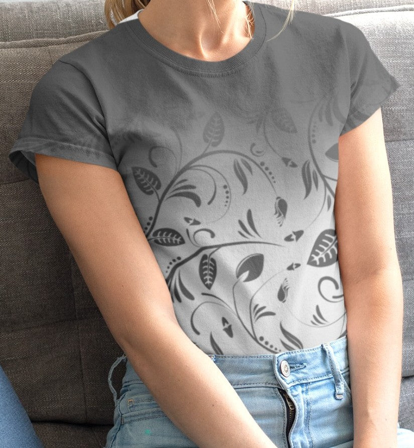 This custom women's handmade tee has a ombre pattern with the top of the shirt being a slate grey color then fading to a light grey at the waistline, there is a floral design with leaves and vines overlayed over the ombre pattern, the leaves are the same color as the dark slate color at the top of the shirt.