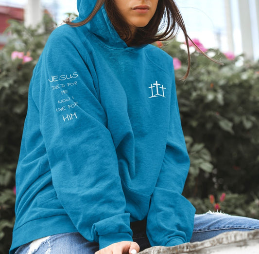 On the front of this custom unisex Christian hoodie are three crosses sitting top of a hill, on the right right arm of the sweater are the words Jesus died for me, now I live for Him in a modern font. 