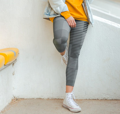 A pair of women's high waisted Christian themed leggings, the pants are light grey  color with black stripes running across the pants, the lines are in different thicknesses from the top to the bottom ankle of the leggings giving it a 3D look when worn, there is a white Jesus cross on the bottom right calf of the pant.