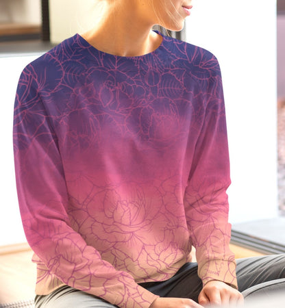 The sweater has a washed ombre pattern starting as a dark purple at the top of the neckline then fading to a light purple then to a bright pink then to a blush pink at the bottom, there is a purple floral pattern imposed on the top of the sweater.