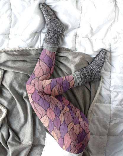 These custom colorful handmade women's leggings have a pattern of multicolored leaves from top to bottom, the leaves are light pink, purple, mauve and beige giving the leggings a vibrant look.
